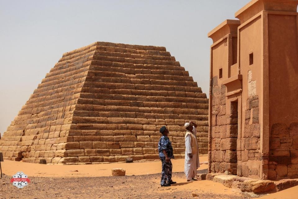 In this Thursday، April 16، 2015 photo، a Sudanese tour guide and a member of the security forces observes a temple at the Meroe pyramids site، in al-Bagrawiya، 200 kilometers (125 miles) north of Khartoum، Sudan. The pyramids at Meroe are deserted despite being a UNESCO World Heritage site like those at Giza in Egypt. (AP Photo/Mosa'ab Elshamy)